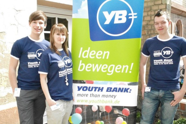 3 Jugendliche mit Youth Bank Plakat  "Ideen bewegen"