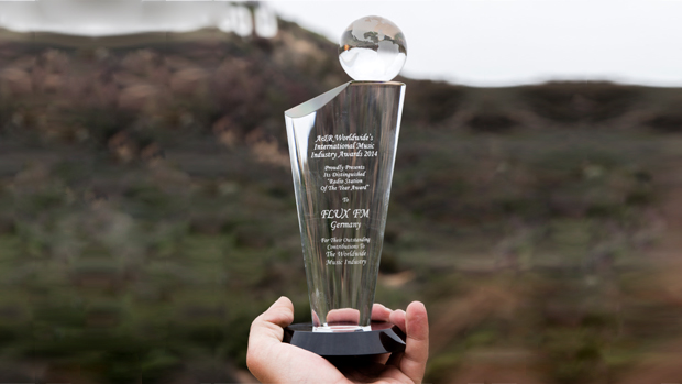 Award aus Glas Nahaufnahme, im Hintergrund Hügel