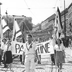 Eine Delegation, bestehend aus jungen jüdischen und arabischen Kommunisten aus Palästina, die im Juli 1947 an einem Aufmarsch bei den Weltfestspielen der Jugend und Studenten in Prag teilnahm. Auf ihrem Banner ist zu lesen: „Die Straße zur Freiheit – ein jüdisch-arabisches Solidaritätsprojekt". Foto: Jakob Kösten