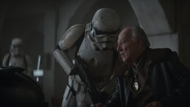 Der Auftraggeber (link) wird von Werner Herzog verkörpert. Er will das kleine Wesen erhalten. (Quelle: © 2019 Lucasfilm Ltd. & ™. All Riights Reserved.)